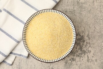 Fototapeta premium Raw semolina in bowl on grey table, top view