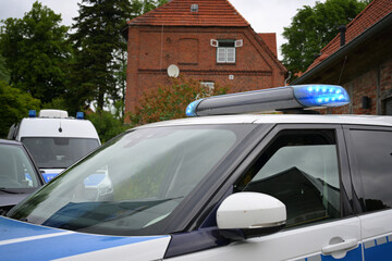Part of a german police car with flashing blue light bar in an old town © Maren Winter