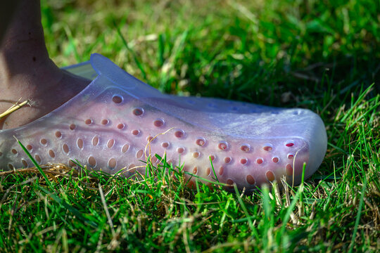 Pied dans des chaussures respirantes en caoutchouc marchant dans l'herbe