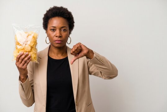 Woman holding a bag of potato chips and giving thumbs down, expressing rejection of junk food