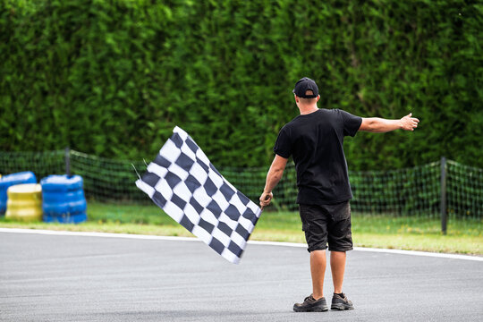 Homme de dos brandit le drapeau &agrave; damier &agrave; l'arriv&eacute;e d'une course