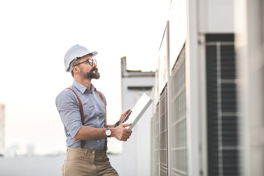 Portrait of Technician Electrical Engineer at rooftop building. Clean and green alternative energy concept.