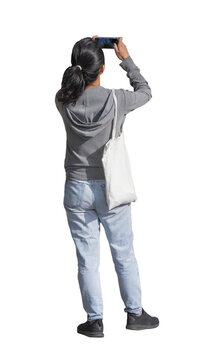 Femme vue de dos photographiant une sc&egrave;ne avec un smartphone, portant un sweat &agrave; capuche gris, un jean clair et un sac en toile &agrave; l&rsquo;&eacute;paule