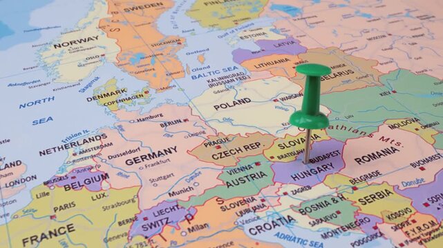 Green push pin marking capital city of Budapest on paper map of Central Europe.