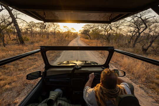 Open-top vehicle on rural dirt road at sunset
