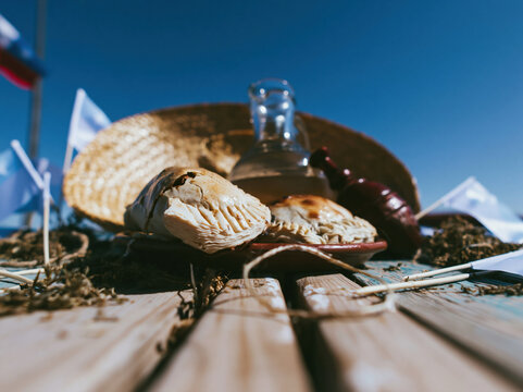 Straw hat and baked empanadas on a rustic table for national holiday celebrations, traditional food and festive cultural event advertising