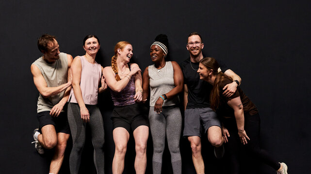 Diverse group of friends enjoying a fitness workout together in a studio, laughing and supportive