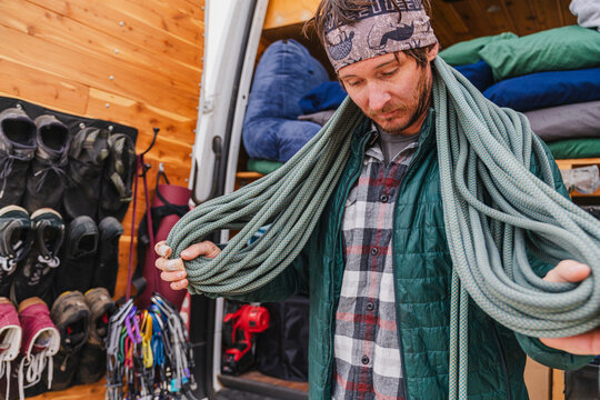 man organizing rock climbing rope by camper van