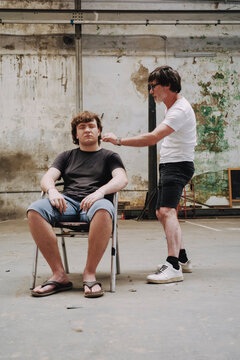 Styling the hair of a teenage boy on flip-flops 