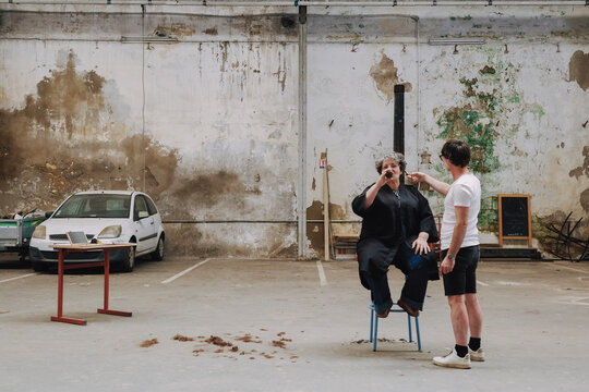 Woman Sitting in a Chair While Another Person Trims her Hair