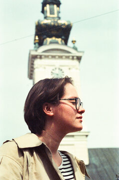 Young Person Stands in Front of Clock Tower on a Sunny Day