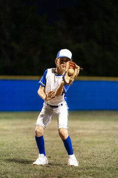 Baseball Player Fields Ball on a Night Game