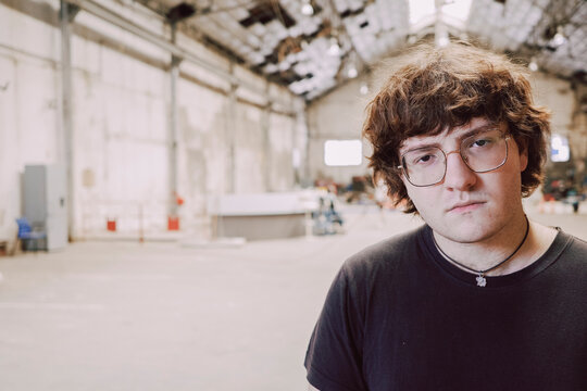 Young Man Stands Confidently in an Empty Industrial Space