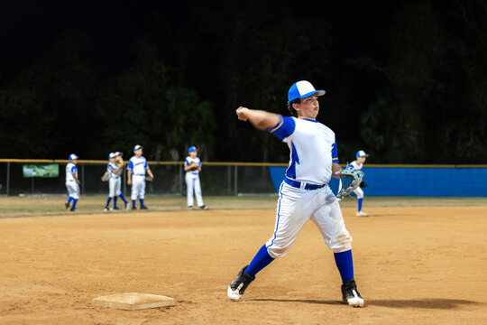 Young baseman Throwing Ball at Night Baseball Game