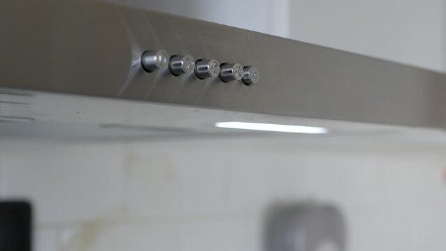Finger Pressing Kitchen Range Hood Power Button Closeup. Man Pressing Stainless Steel Range Hood Switch Detail.