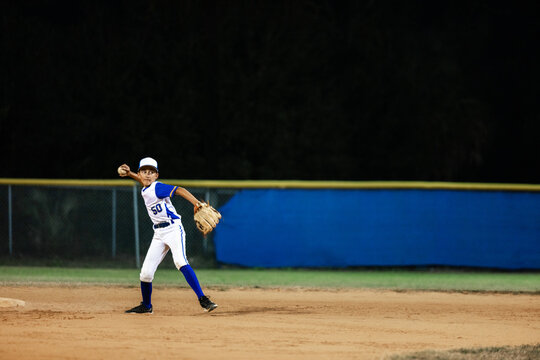 Young Fielder Prepares to Throw Ball on Night Field
