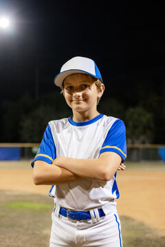 Young Baseball Player Poses Proudly on a Field at Night