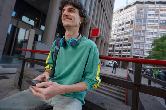 Gen Z guy relaxes with phone near subway station in Italy
