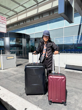 senior asian traveler standing with suitcases at airport