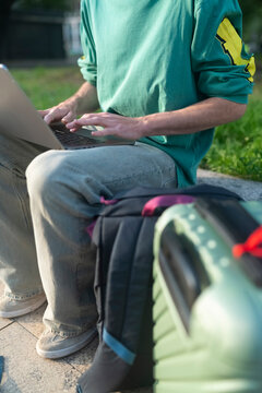 Gen Z traveler working on laptop in Italy with trolley by side