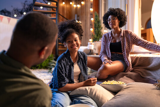 Family talking together with popcorn on patio with projector setup

