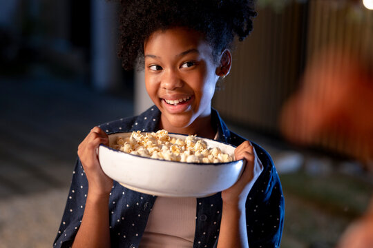 Smiling girl holds bowl of popcorn.