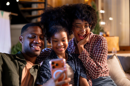 Family smiles at phone screen, sharing a joyful moment.