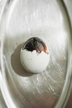 Egg With a Dark Shell and Partial Break on a Silver Tray