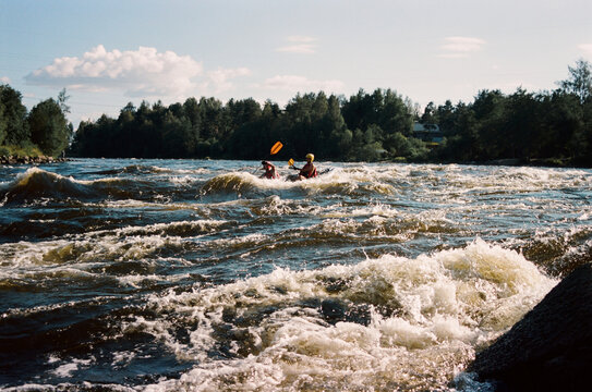 Kayakers move through rough waters in summer