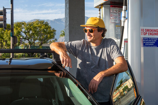 Man Standing in Door of Car at Gas Station