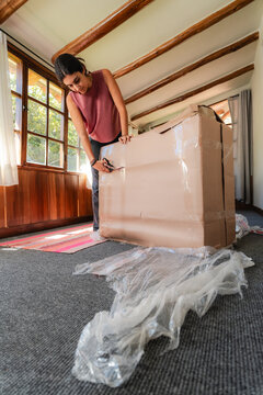 young Woman Unboxing Large Fragile Box at Home