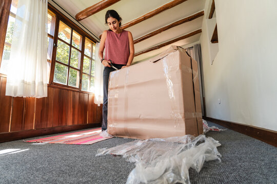 young Woman Unpacking Large Fragile Box at Home