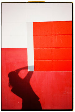 Woman Shadow Taking Photo on Red and White Wall
