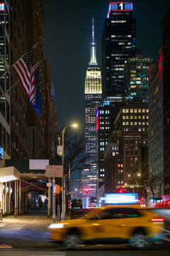 Vibrant NYC nightscape with taxi, flags and empire state