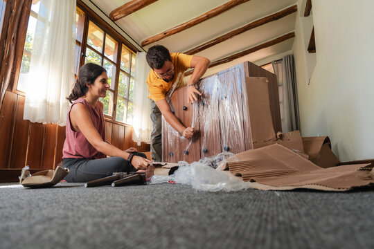 Young Couple Unboxing New Furniture Delivery at Home
