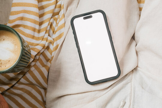 Blank phone screen beside coffee at home