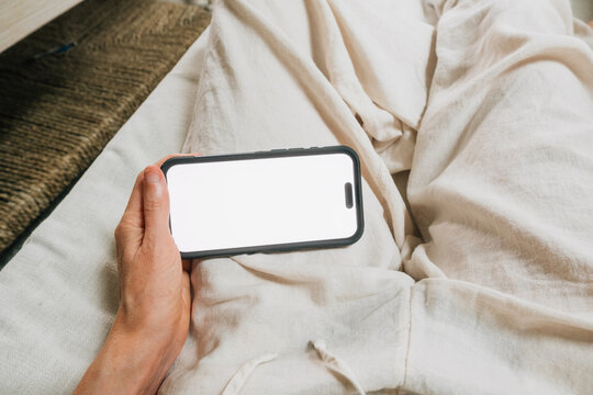 POV using horizontal phone with blank white screen on couch