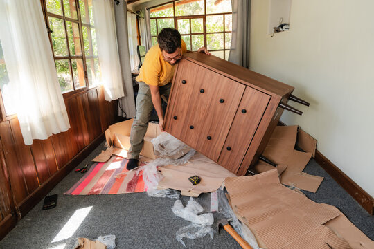 Young Man Lifting New Wooden Dresser, moving to new home