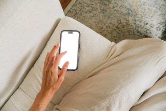 POV reaching for phone while relaxing on couch at home