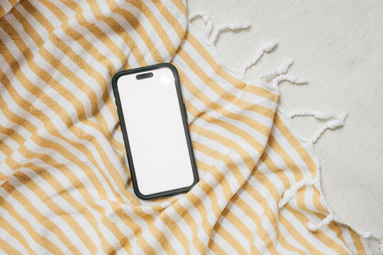 Blank phone screen on striped blanket at home