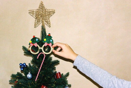 Teenager girl's hand hanging toys on the Christmas tree.