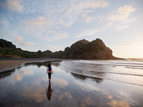 A woman walking along an empty beach at dusk