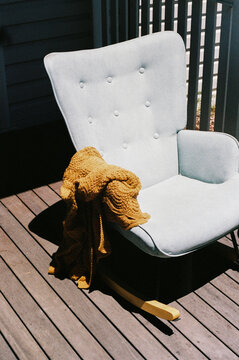 Empty rocking chair draped with a soft knitted blanket