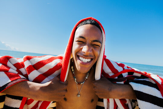 Man laughing enjoying sunny beach day with striped towel
