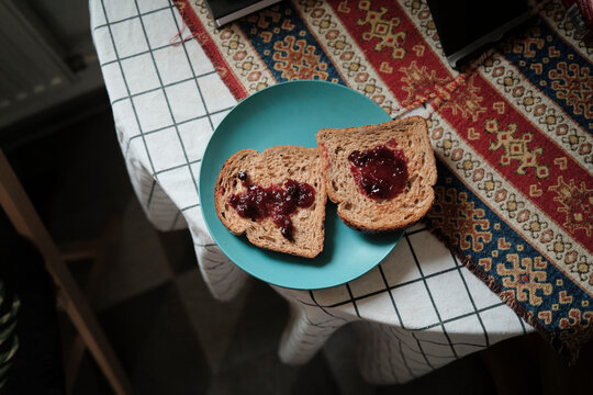 Bread with jam on a blue plate on a patterned tablecloth