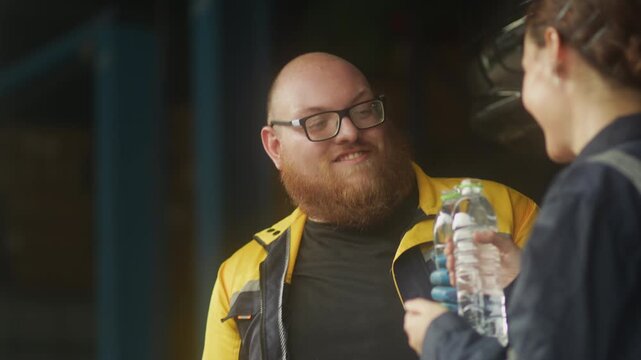 Caucasian male mechanic with glasses and a beard works alongside a female technician, reviewing a digital tablet and giving a thumbs-up. This high-energy commercial imagery represents gender diversity