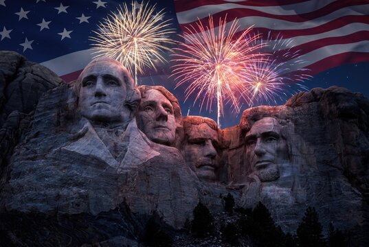 Iconic Mount Rushmore National Memorial illuminated by vibrant fireworks and the American flag.