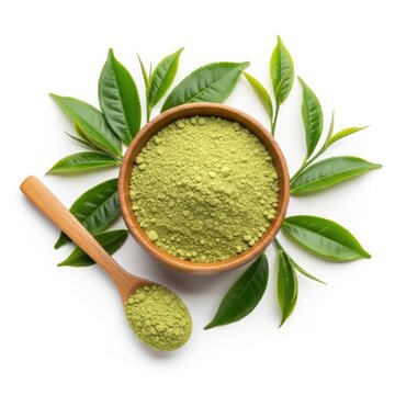 A wooden bowl filled with vibrant green matcha powder alongside a wooden spoon overflowing with powder and surrounded by fresh green tea leaves on a white background