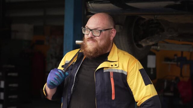 Caucasian male mechanic with glasses and a beard works alongside a female technician, reviewing a digital tablet and giving a thumbs-up. This high-energy commercial imagery represents gender diversity