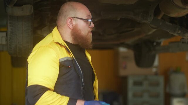 Caucasian male mechanic with glasses and a beard works alongside a female technician, reviewing a digital tablet and giving a thumbs-up. This high-energy commercial imagery represents gender diversity